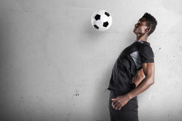 Uomo nero che gioca a calcio su sfondo strutturato — Foto Stock
