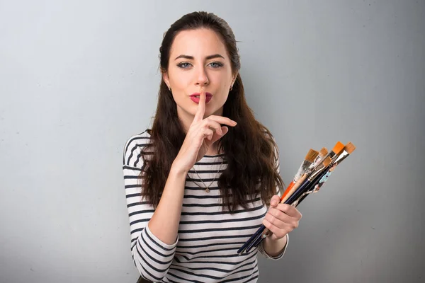 Jonge kunstenaar vrouw maken stilte gebaar op grijze achtergrond — Stockfoto