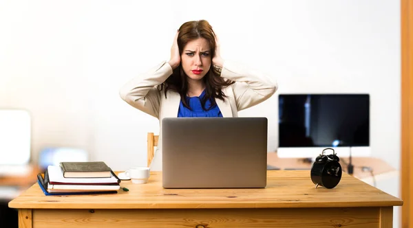 Affärskvinna arbetar med sin laptop och täcker öronen i — Stockfoto