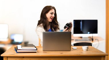 Onu laptop ile çalışma ve vintage saat tutan bir iş kadını