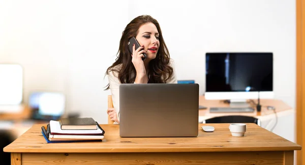 Geschäftsfrau arbeitet mit Laptop und Handy in der Hand — Stockfoto