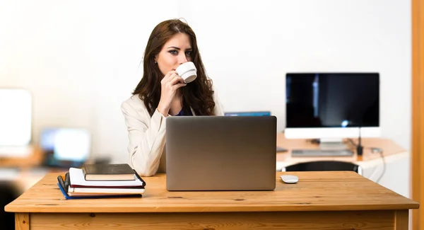 Επιχειρήσεων γυναίκα λειτουργεί με το laptop της και κρατώντας ένα φλιτζάνι καφέ — Φωτογραφία Αρχείου