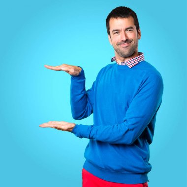 Bir şey renkli arka plan üzerinde tutan yakışıklı genç