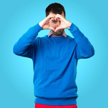 Yakışıklı genç adam renkli bac elleri ile bir kalp yapma