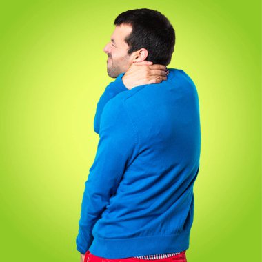 Renkli arka plan üzerinde boyun ağrısı ile yakışıklı genç