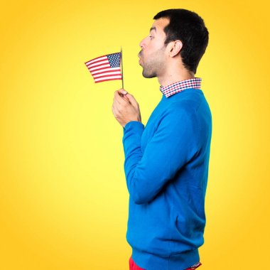 Bir Amerikan bayrağı üzerinde renkli backgrou tutan yakışıklı genç