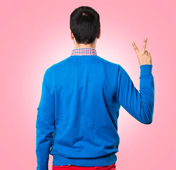 Handsome young man counting two on colorful background — Stock Photo, Image