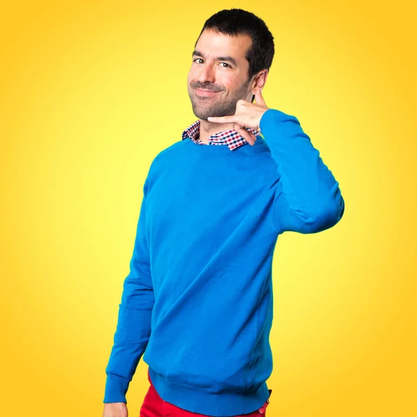 Hombre joven guapo haciendo gesto de teléfono sobre fondo colorido — Foto de Stock