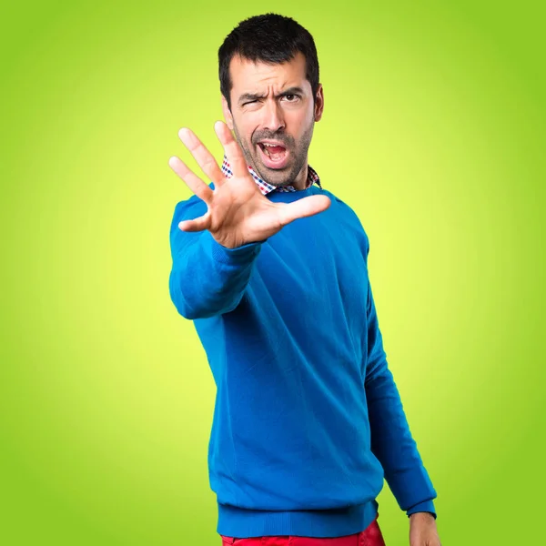 Hombre joven guapo haciendo señal de stop sobre fondo colorido — Foto de Stock