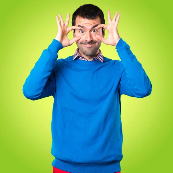 Guapo joven mostrando algo sobre fondo colorido — Foto de Stock