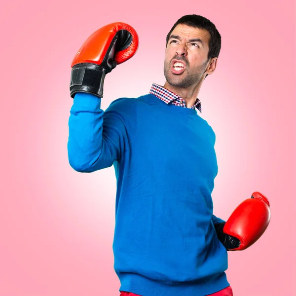 Guapo joven con guantes de boxeo sobre fondo colorido — Foto de Stock