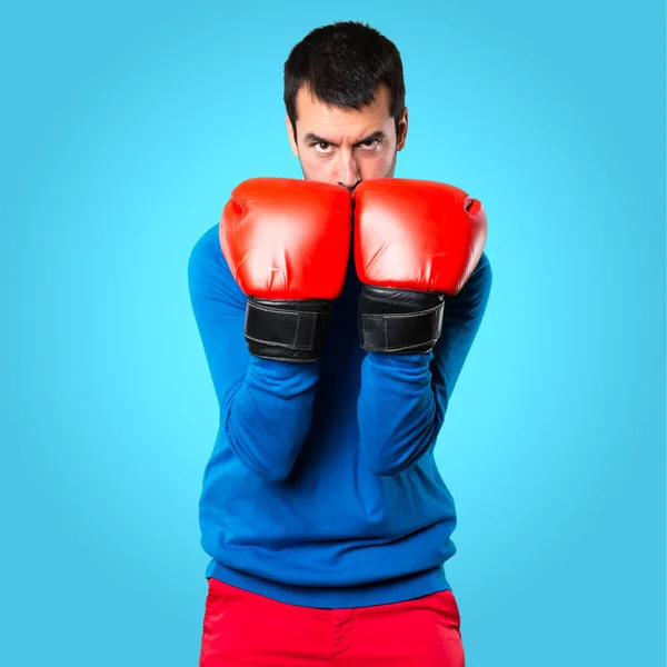 Guapo joven con guantes de boxeo sobre fondo colorido —  Fotos de Stock