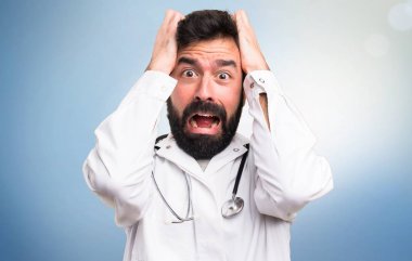 Mavi arka plan üzerinde hayal kırıklığına uğramış genç doktor