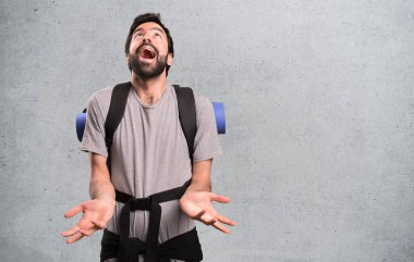 Yakışıklı backpacker dokulu arka plan üzerinde yalvaran
