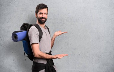 Yakışıklı backpacker bir şey dokulu arka plan üzerinde sunulması