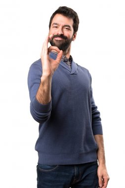 Beyaz arka plan üzerinde oturum Tamam yapma sakallı yakışıklı esmer adam