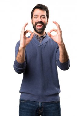 Beyaz arka plan üzerinde oturum Tamam yapma sakallı yakışıklı esmer adam