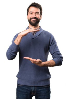 Bir şey beyaz arka plan üzerinde tutan sakallı yakışıklı esmer adam