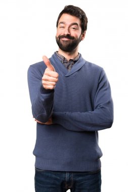 Beyaz arka plan üzerinde başparmak ile sakallı yakışıklı esmer adam