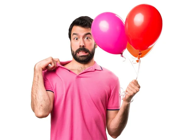 Όμορφος νεαρός άνδρας με πυρετό κρατώντας μπαλόνια πάνω από απομονωμένες λευκό φόντο — Φωτογραφία Αρχείου