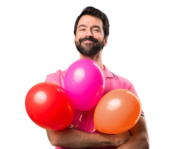 Όμορφος νεαρός άνδρας, κρατώντας τα μπαλόνια πάνω από απομονωμένες λευκό φόντο — Φωτογραφία Αρχείου