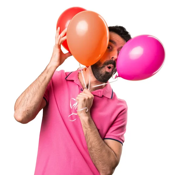 Schöner junger Mann mit Luftballons über isoliertem weißem Hintergrund — Stockfoto