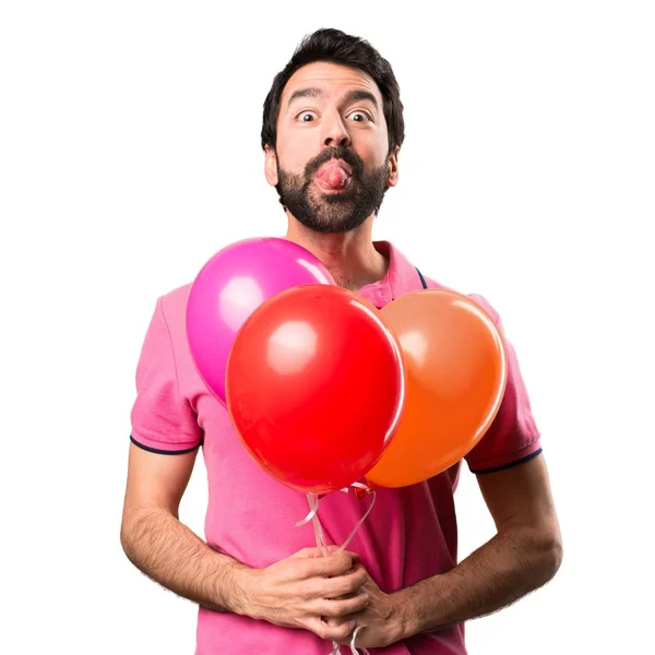 Knappe jonge man een grap bedrijf ballonnen maken over geïsoleerde witte achtergrond — Stockfoto