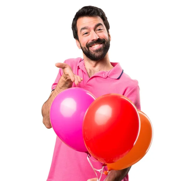 Όμορφος νεαρός άνδρας, κρατώντας τα μπαλόνια πάνω από απομονωμένες λευκό φόντο — Φωτογραφία Αρχείου
