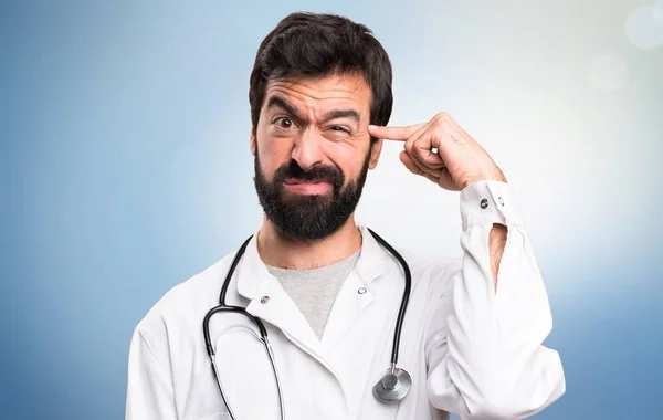 Молодой доктор делает сумасшедший жест на синем фоне — стоковое фото