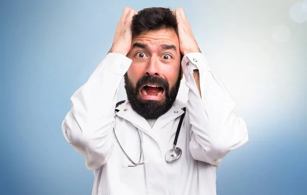 Frustrado jovem médico em fundo azul — Fotografia de Stock