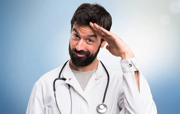 Young doctor saluting on blue background — Stock Photo, Image