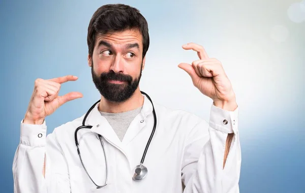 Junge Ärztin macht winziges Schild auf blauem Hintergrund — Stockfoto