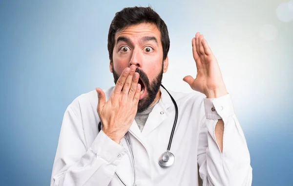 Молодой доктор делает неожиданный жест на синем фоне — стоковое фото