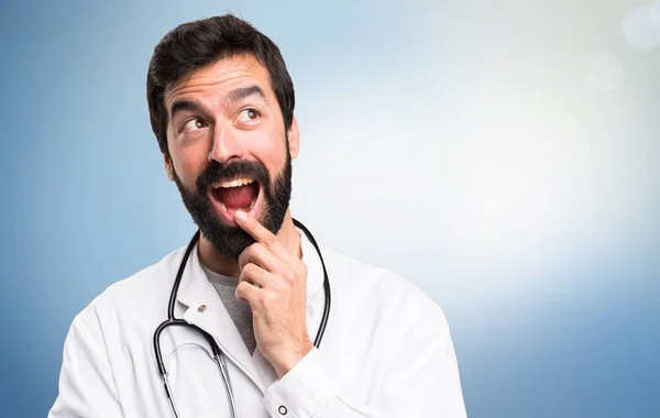 Ung läkare gör överraskning gest på blå bakgrund — Stockfoto