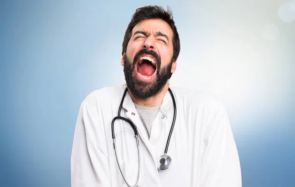 Jonge dokter schreeuwen op blauwe achtergrond — Stockfoto