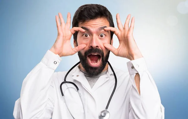 Jovem médico mostrando algo no fundo azul — Fotografia de Stock