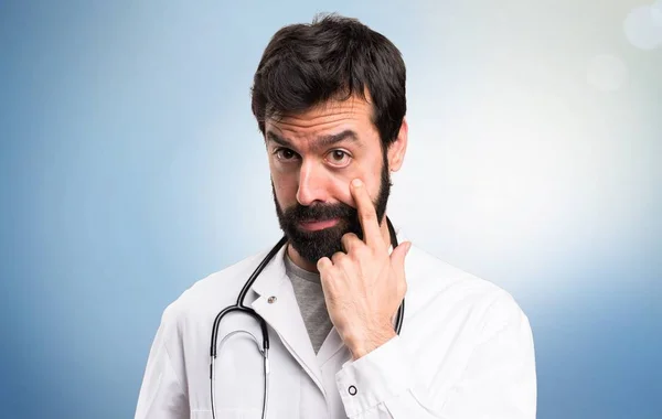 Young doctor showing something on blue background — Stock Photo, Image