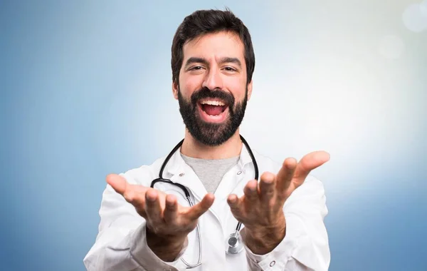 Junger Arzt präsentiert etwas auf blauem Hintergrund — Stockfoto