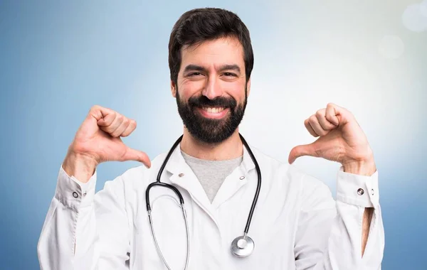 Junger Arzt stolz auf sich selbst auf blauem Hintergrund — Stockfoto