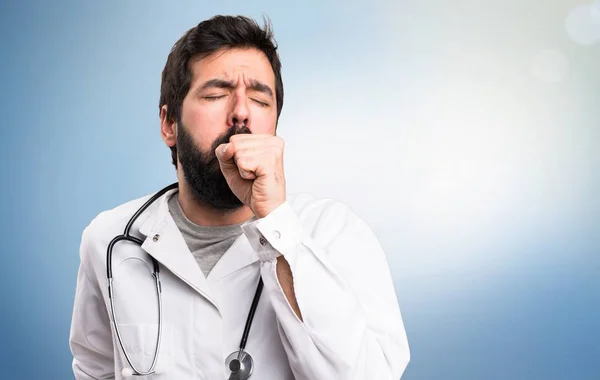 Jeune médecin tousse beaucoup sur fond bleu — Photo