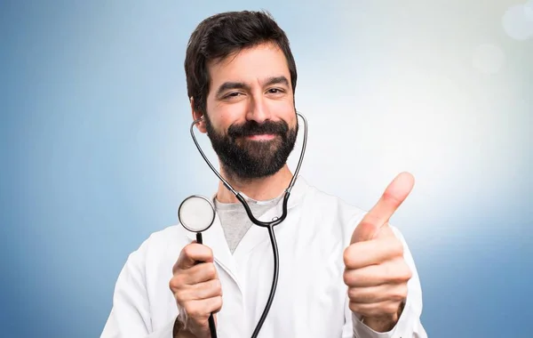 Unga läkare med stetoskop på blå bakgrund — Stockfoto