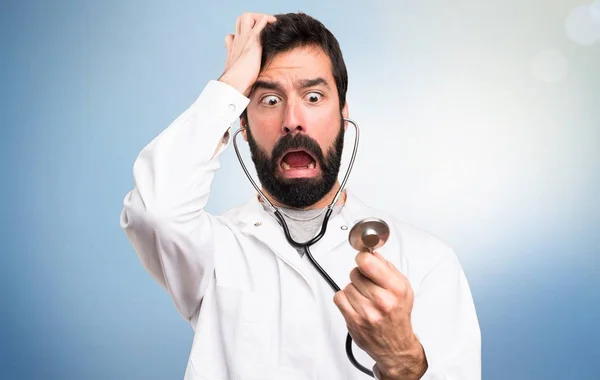 Médico joven con estetoscopio sobre fondo azul —  Fotos de Stock