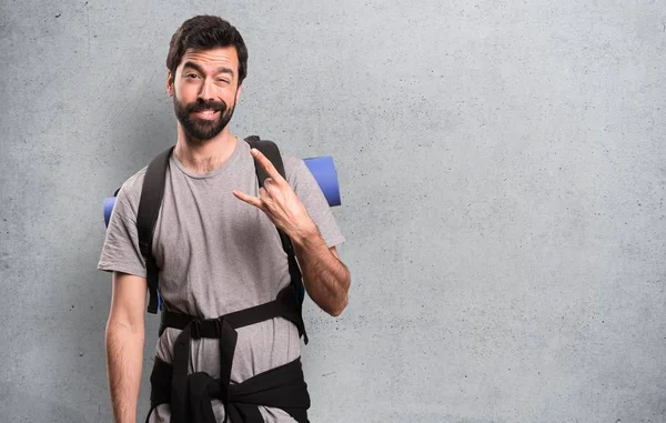 Handsome backpacker making rock gesture on textured background — Stock Photo, Image