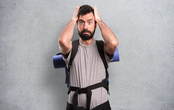 Frustrated handsome backpacker on textured background — Stock Photo, Image