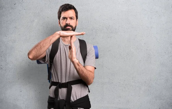 Handsome backpacker making time out gesture on textured background — Stock Photo, Image