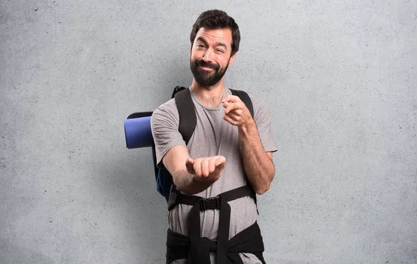 Handsome backpacker holding something on textured background — Stock Photo, Image