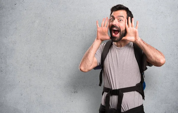 Schöner Backpacker macht überraschende Geste auf strukturiertem Hintergrund — Stockfoto