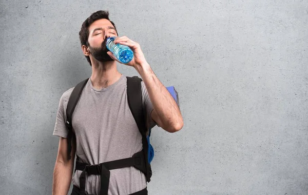 Stilig backpacker med en flaska vatten på texturerat bakgrund — Stockfoto