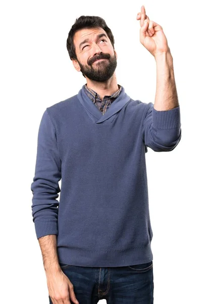 Knappe brunette man met baard met zijn vingers oversteken op witte achtergrond — Stockfoto