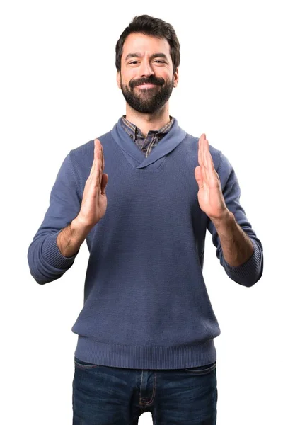 Handsome brunette man with beard holding something on white background — Stock Photo, Image